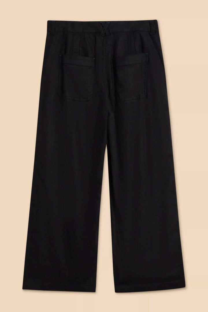 Pantalon Harper en noir à jambe large, avec deux poches arrière, vue arrière sur fond beige.