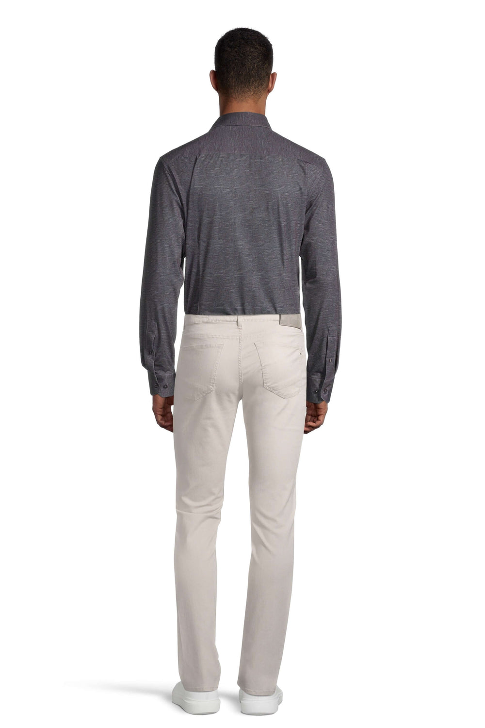 Homme portant une chemise grise et un pantalon beige, vue de dos, style moderne et décontracté.