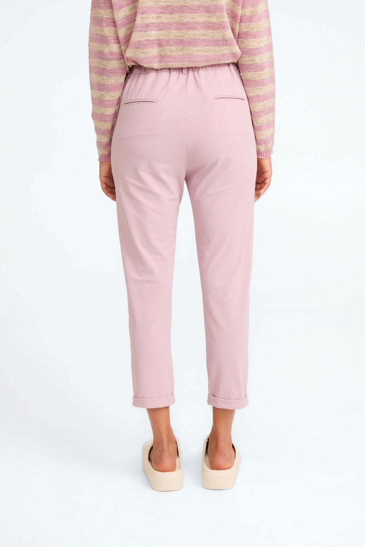 Pantalon Lena 7/8e rose, taille haute avec poches, porté avec un haut rayé, style moderne et confortable.