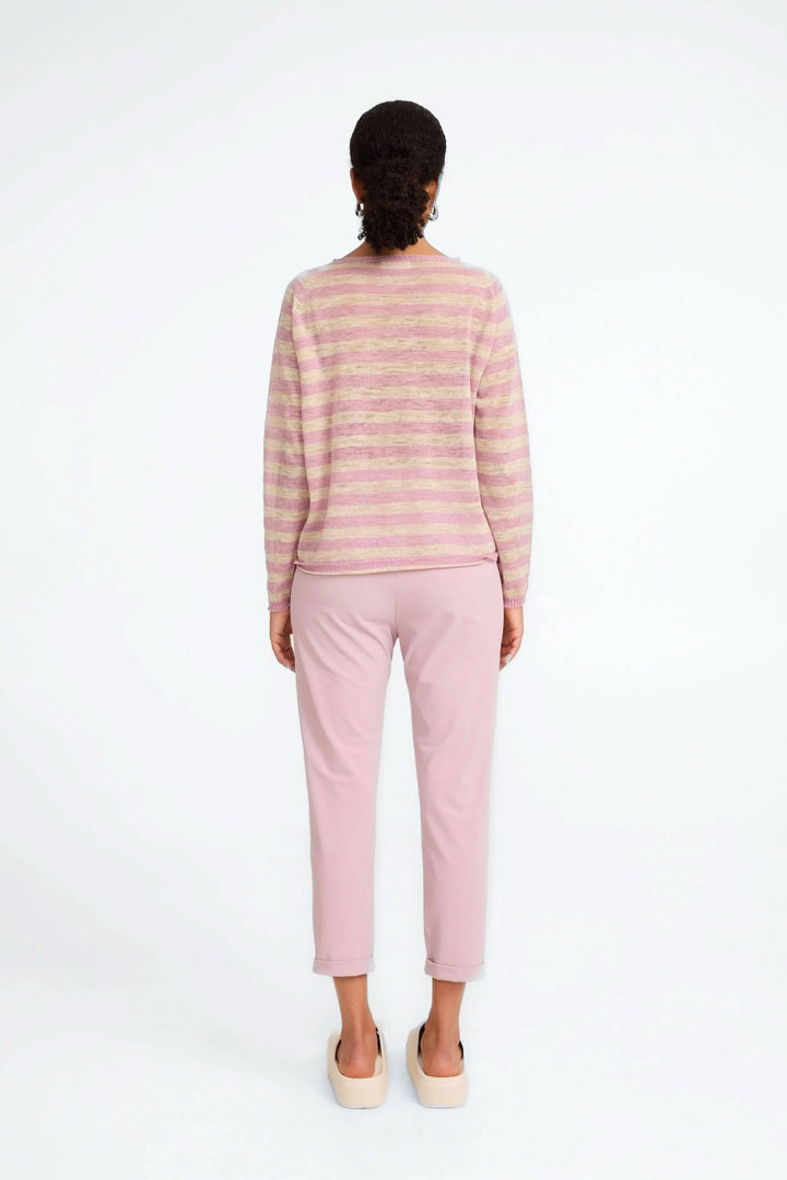 Femme de dos portant un pantalon 7/8e rose avec un pull rayé, style moderne et décontracté.