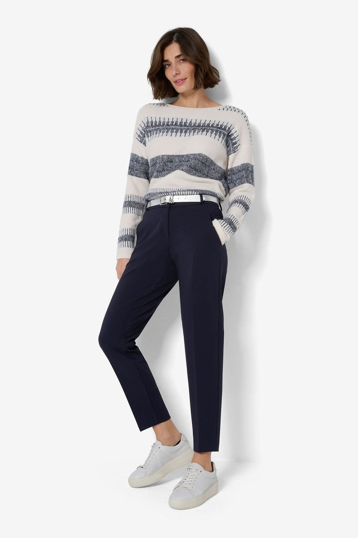 Femme portant un pantalon chino bleu marine avec un pull rayé et des chaussures blanches, style décontracté.