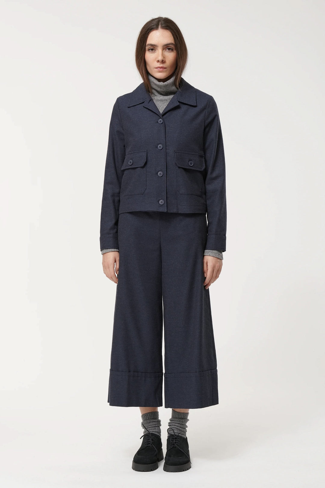 Femme portant un pantalon ample culotte et une veste moderne, style urbain, confort et élégance.