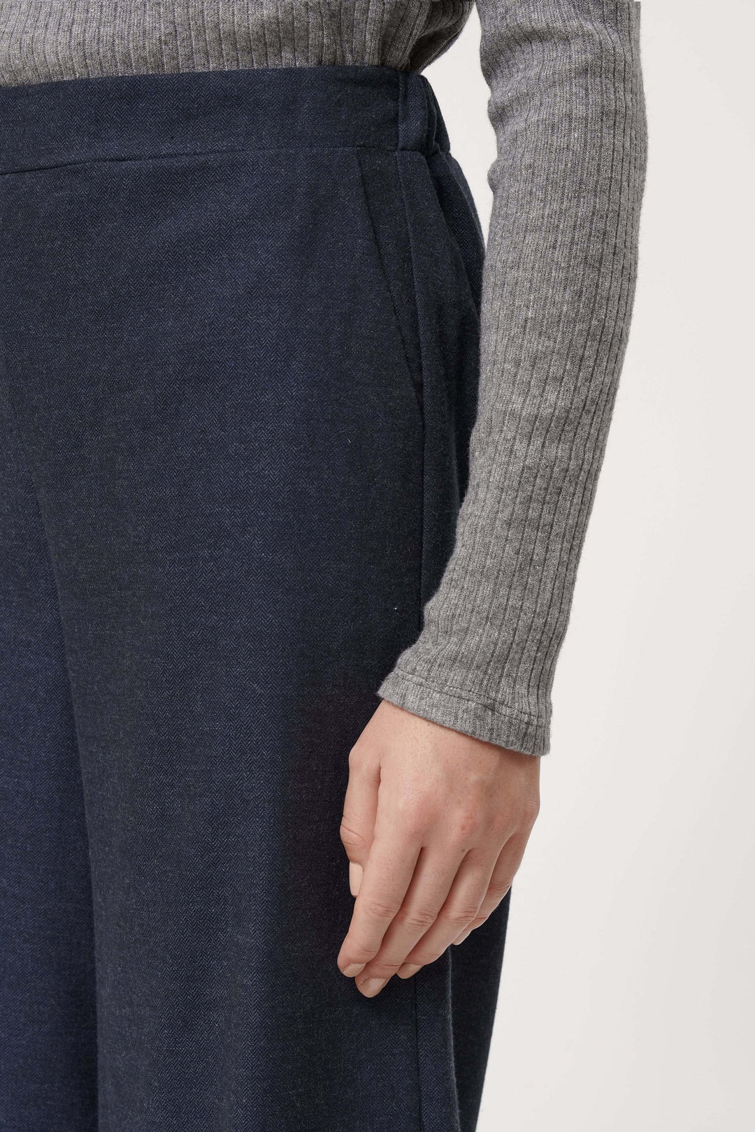 Détail du pantalon Sophio avec coupe large, taille élastique et tissu fluide, porté avec un pull gris.