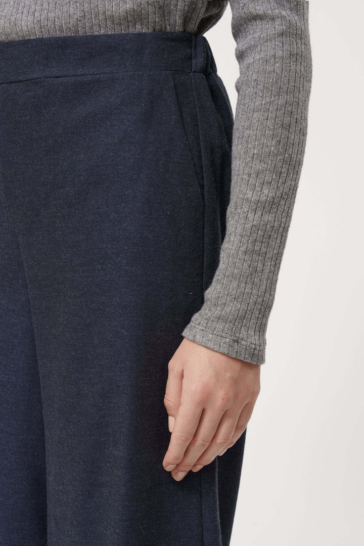 Détail du pantalon Sophio avec coupe large, taille élastique et tissu fluide, porté avec un pull gris.