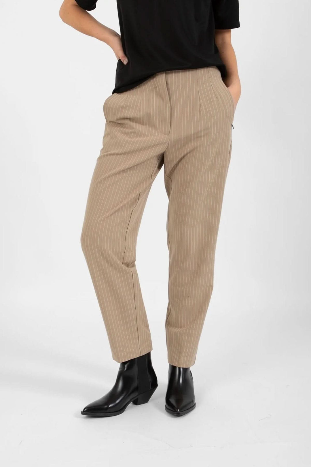 Pantalon Stella beige à rayures, élégant, avec poches, porté avec un top noir.
