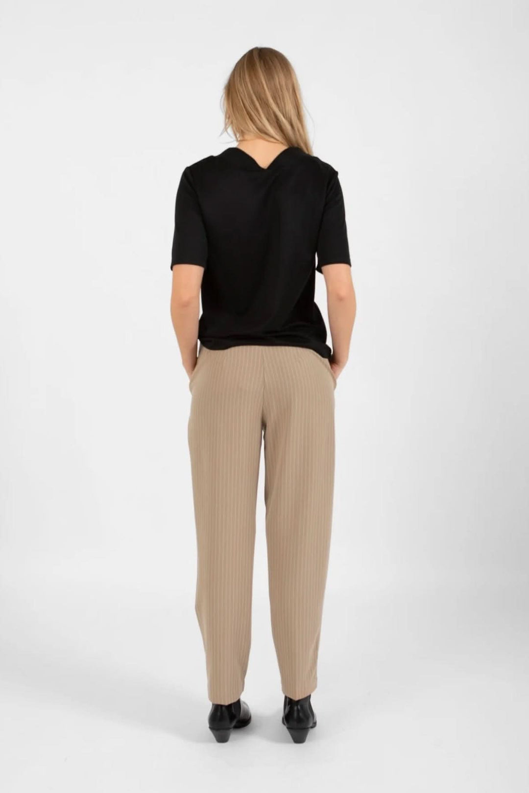 Femme vue de dos portant un pantalon Stella beige et un top noir, affichant un style élégant et décontracté.