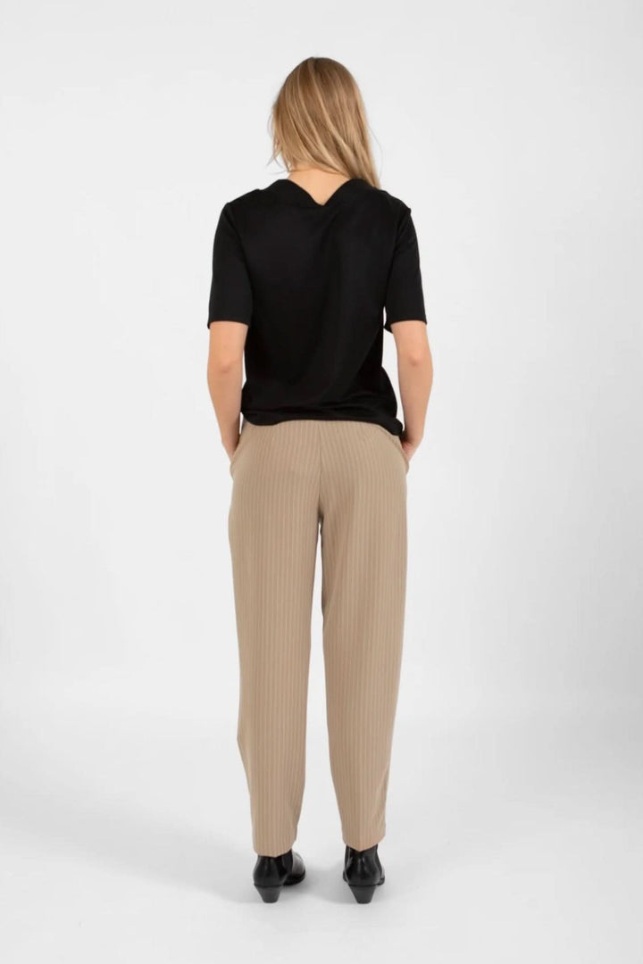 Femme vue de dos portant un pantalon Stella beige et un top noir, affichant un style élégant et décontracté.