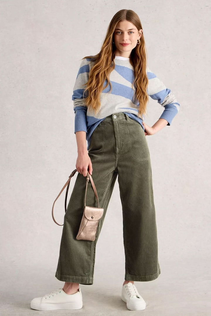 Femme portant le Pantalon Tia en velours côtelé avec coupe évasée, taille haute, style moderne et décontracté.