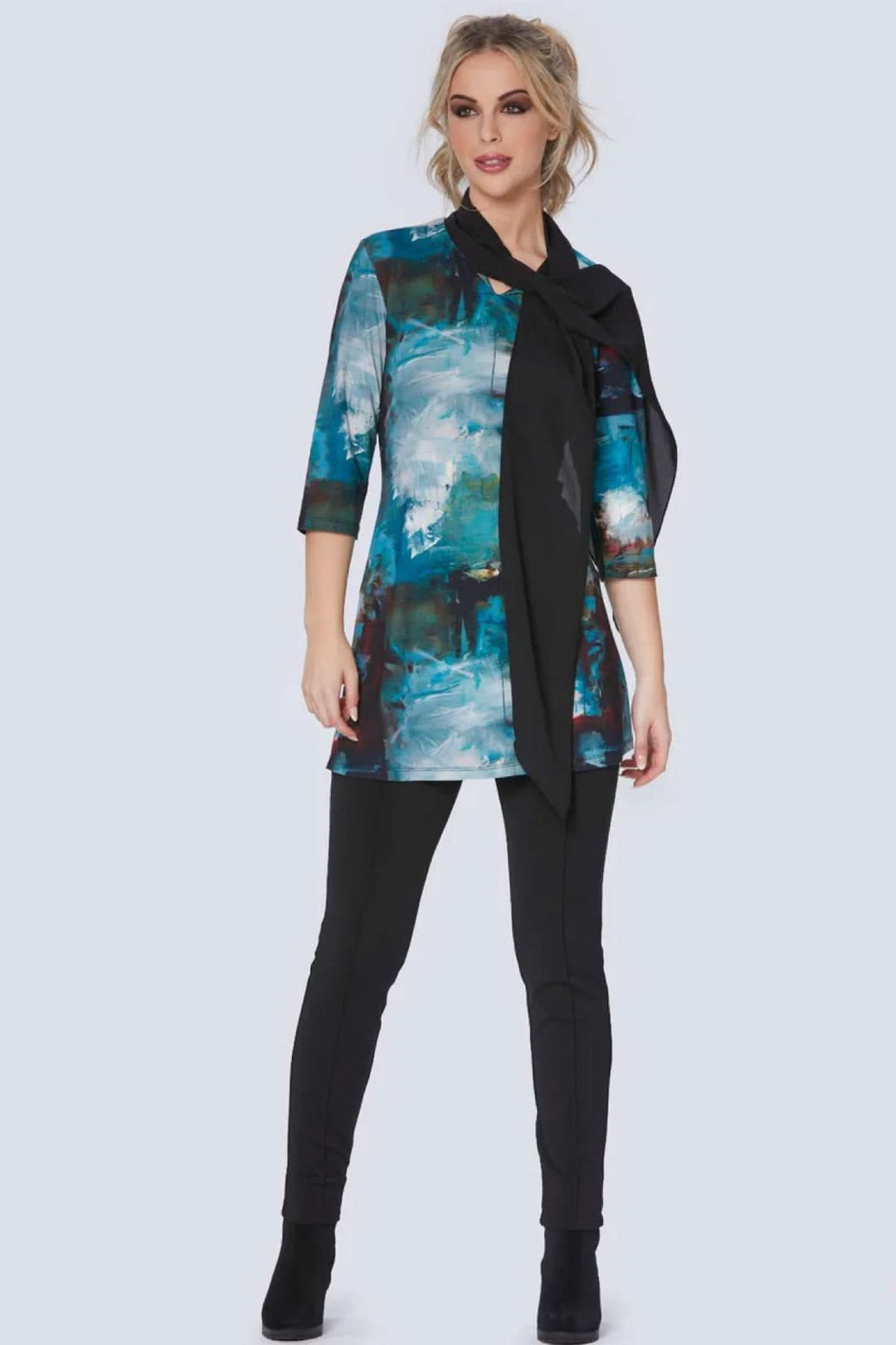 Modèle féminin portant une tunique bleue à imprimé artistique avec un pantalon slim noir.