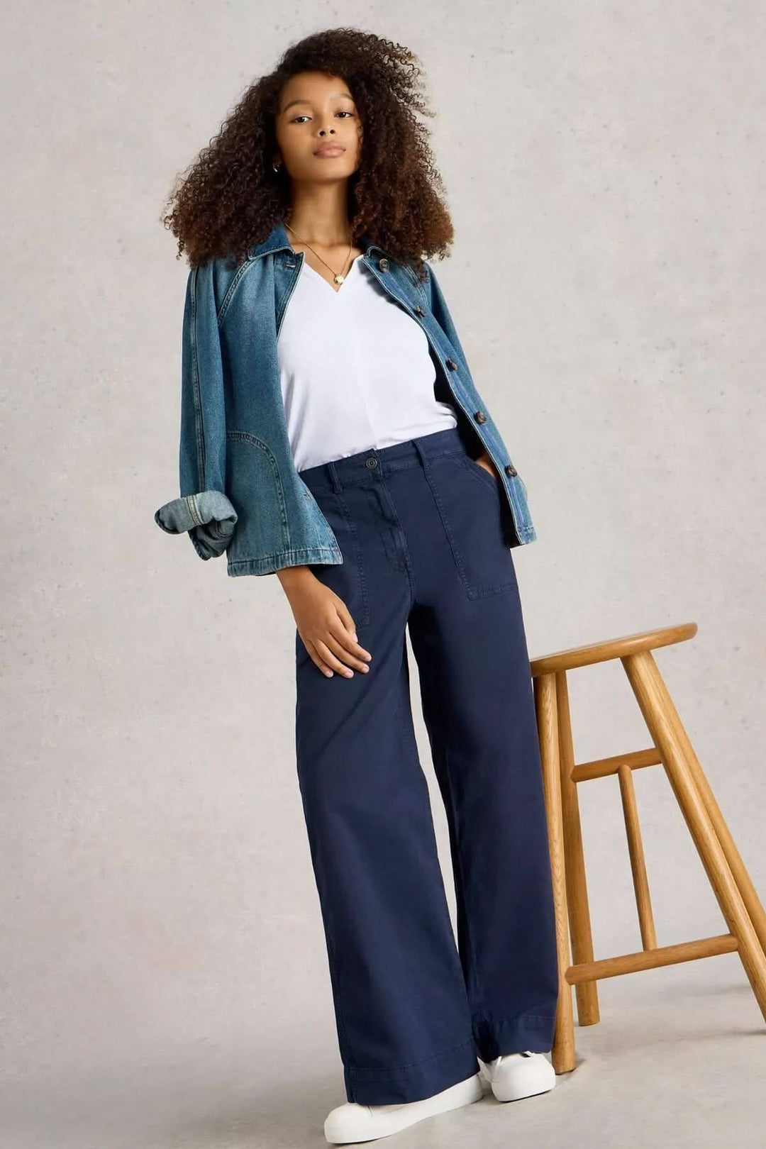 Femme portant un pantalon ample bleu marine avec une veste en jean et t-shirt blanc, style décontracté et moderne.