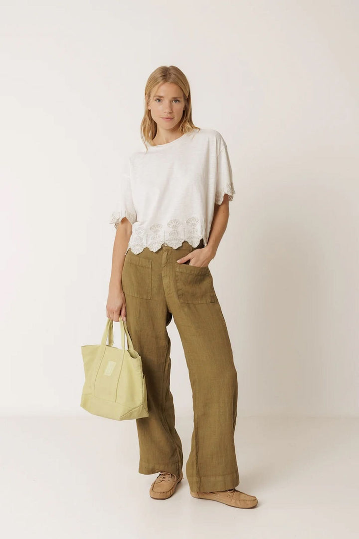 Femme portant un pantalon ample en lin à poches plaquées avec un haut blanc et un sac à main jaune