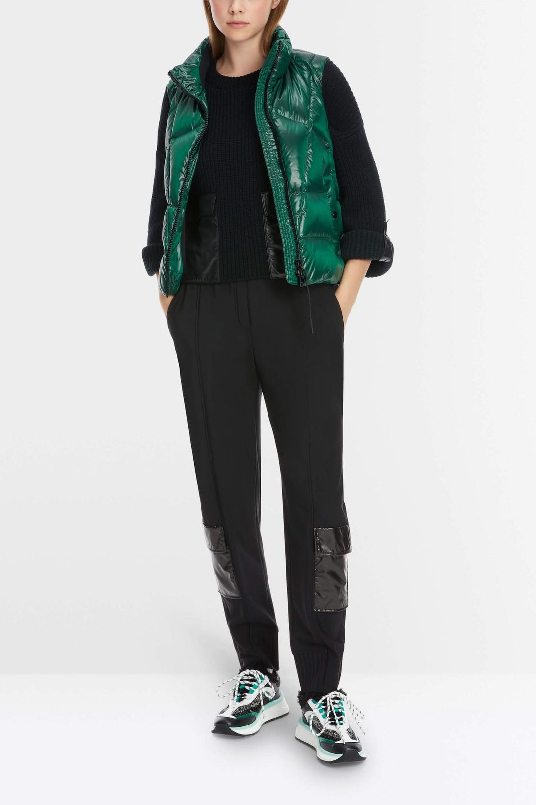 Femme portant un pantalon noir avec poches et un gilet vert, style décontracté et utilitaire.