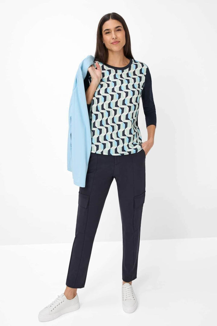 Femme portant un pantalon ceinturé Morris, style jogger 7/8 avec un haut à motifs géométriques.