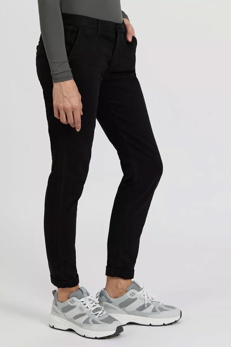Pantalon chino Sandy noir, style décontracté avec poches, porté avec des sneakers blanches.
