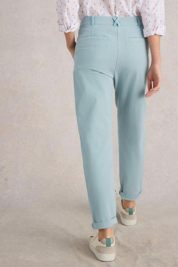 Pantalon chino long bleu clair avec ourlets retroussés, vue arrière, associé à des souliers blancs.