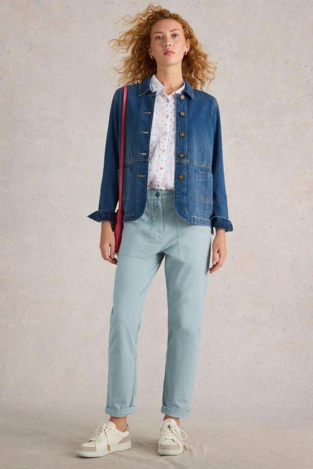 Femme en pantalon chino bleu clair avec chemise légère et veste en jean, style décontracté et élégant.
