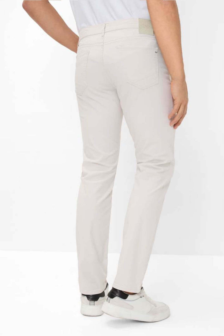 Pantalon cinq poches élégante coupe droite beige, vue arrière, associé à des baskets blanches.
