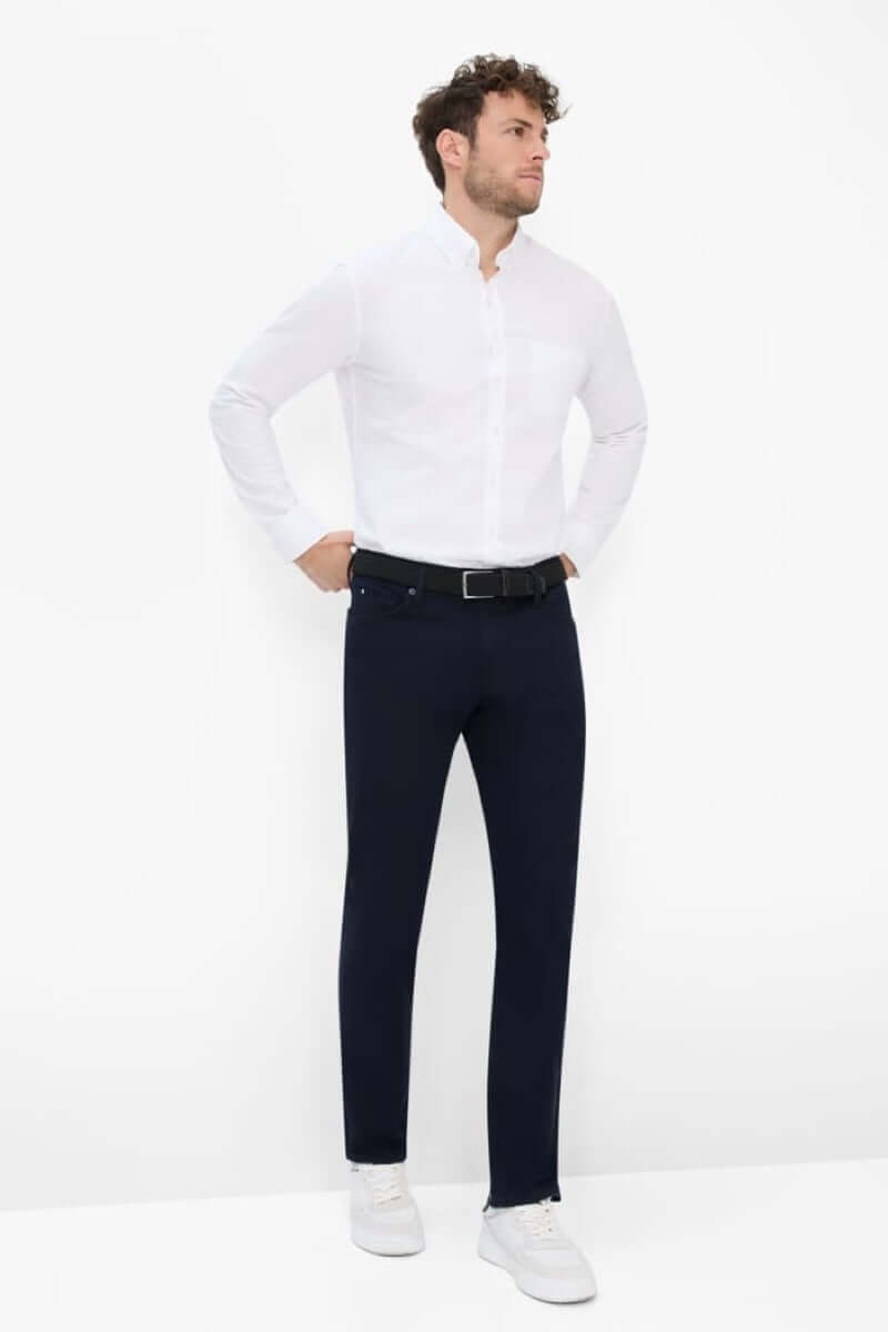 Homme portant un pantalon cinq poches moderne avec une chemise blanche, style élégant et décontracté.