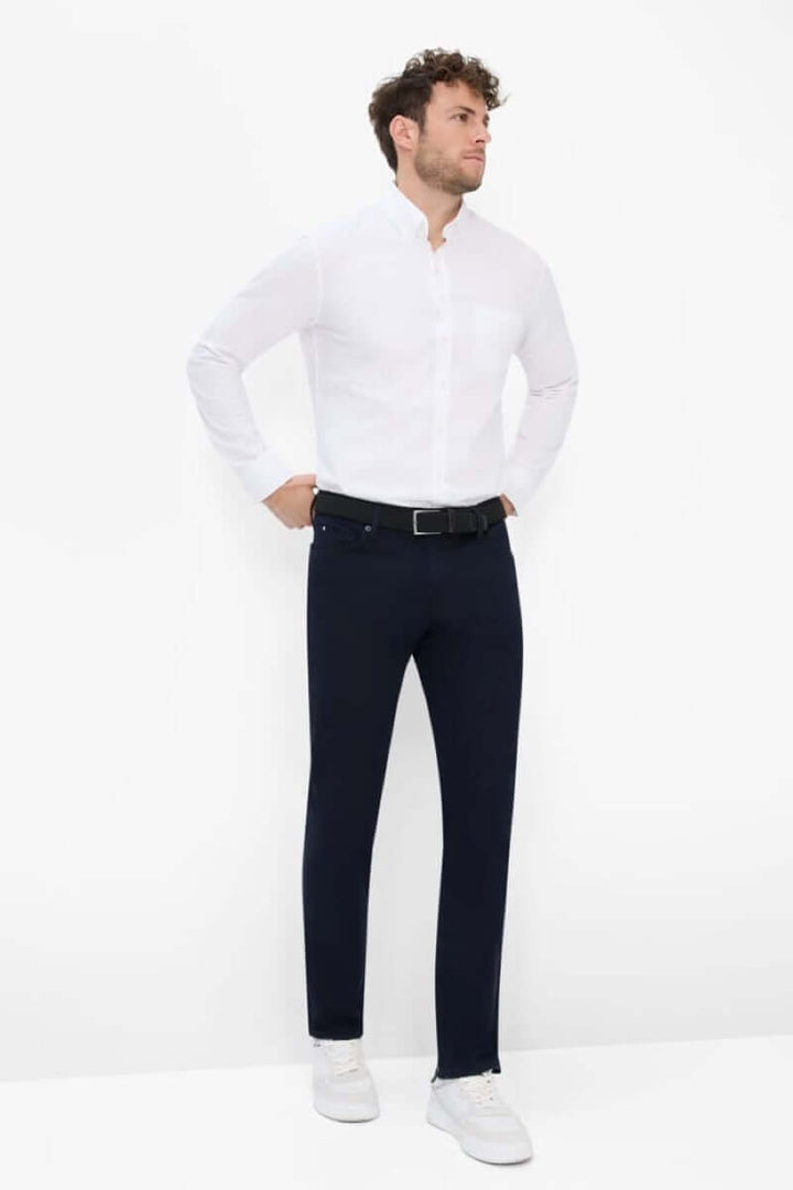Homme portant un pantalon cinq poches moderne avec une chemise blanche, style élégant et décontracté.