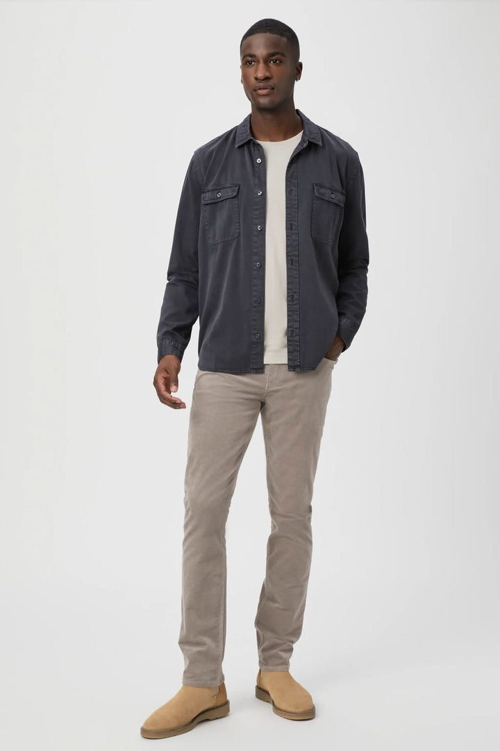 Homme portant un pantalon corduroy beige avec une chemise grise, style décontracté et moderne.