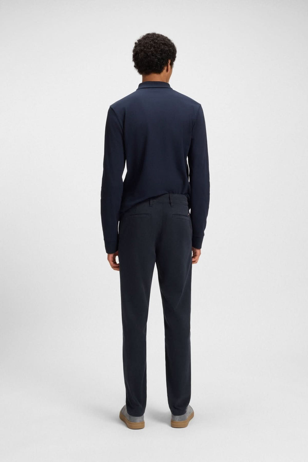Homme vu de dos portant un pantalon fuselé et un polo bleu marine, mix parfait de confort et d'élégance.