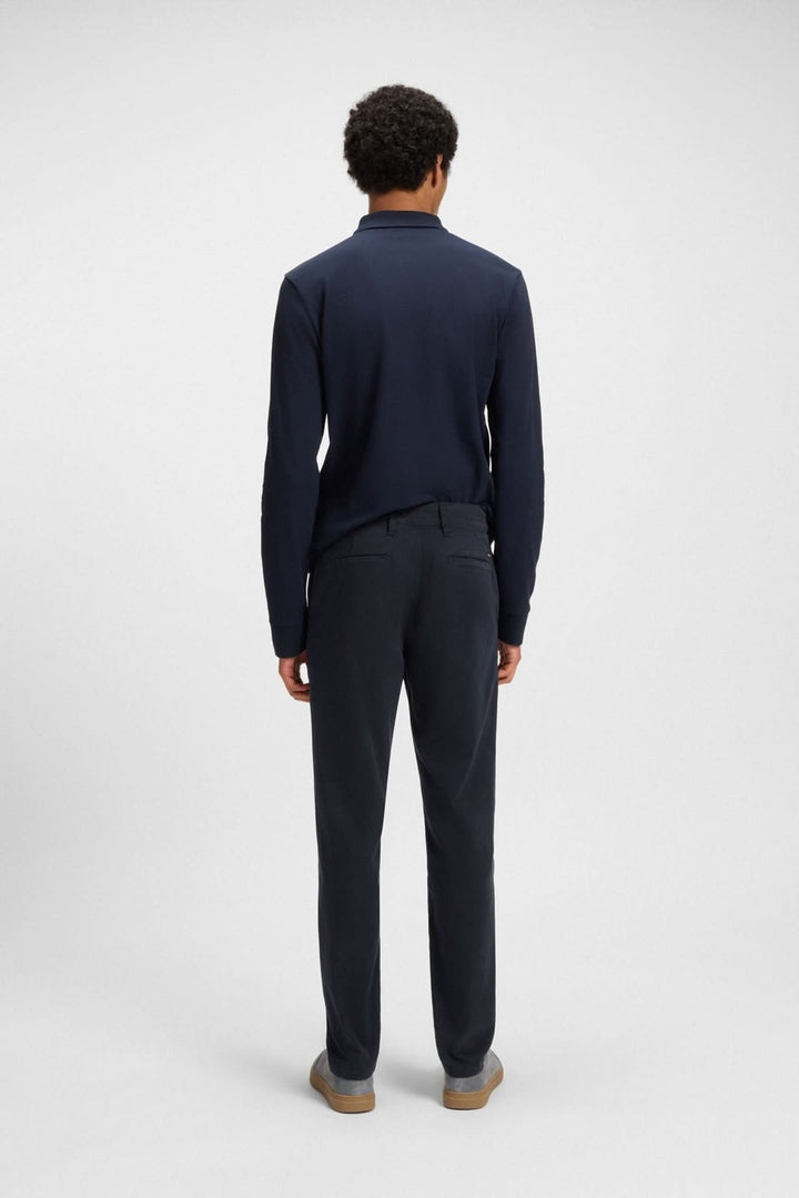 Homme vu de dos portant un pantalon fuselé et un polo bleu marine, mix parfait de confort et d'élégance.