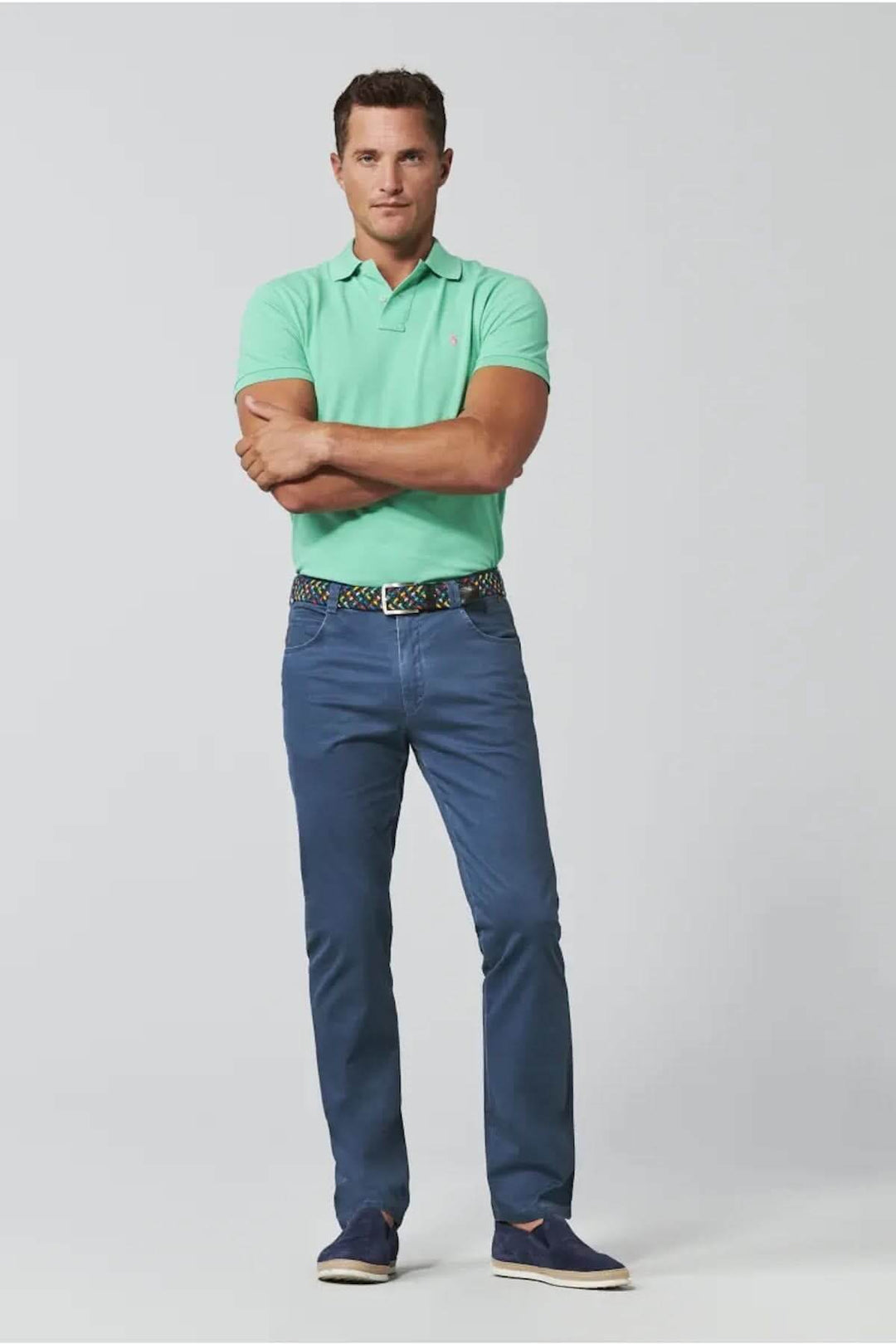Homme en polo vert et pantalon décontracté bleu, style moderne et urbain, look confortable et polyvalent.