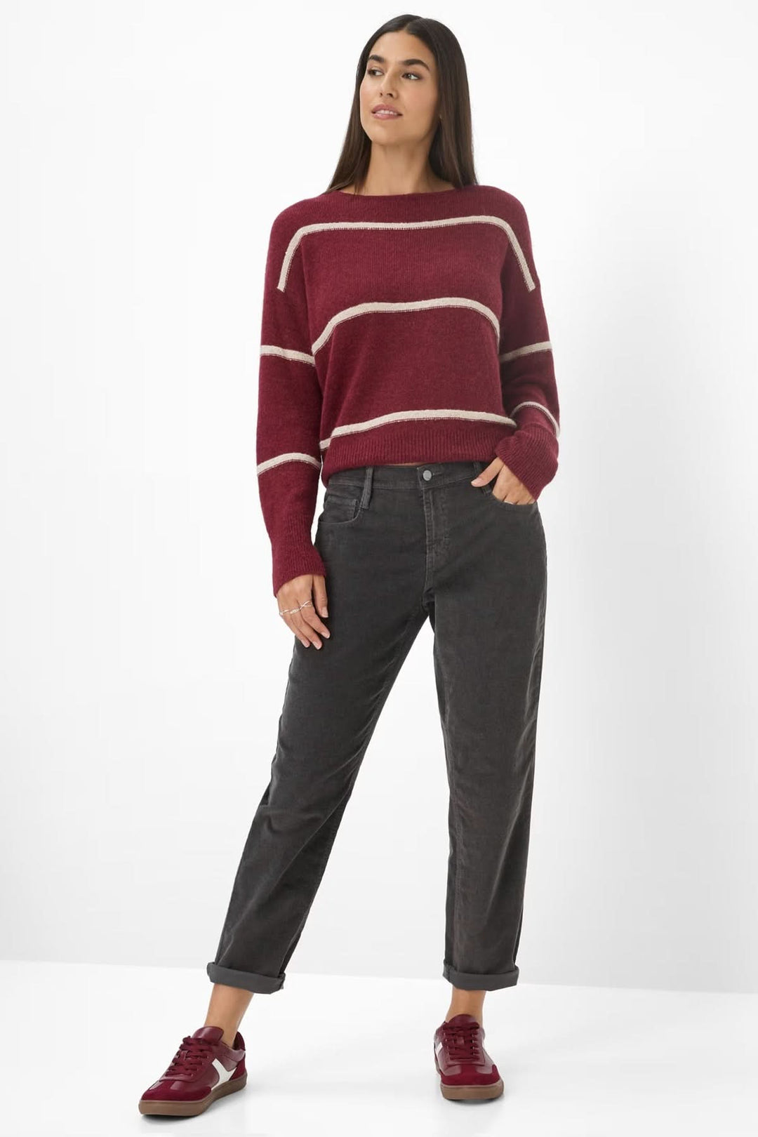 Femme portant un Pantalon de style Mary coupe décontractée, taille mi-haute, jambes fuselées, avec pull ample et baskets rouges.