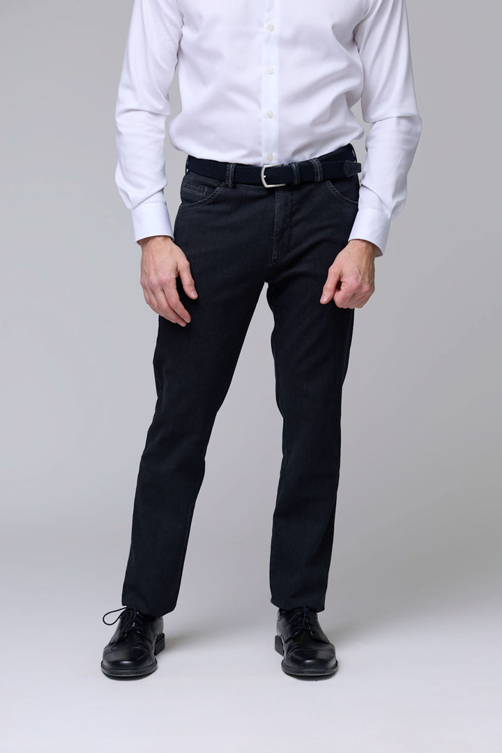 Homme portant un pantalon denim extensible noir, coupe ajustée avec ceinture et poches classiques. Parfait pour un look soigné et confortable.