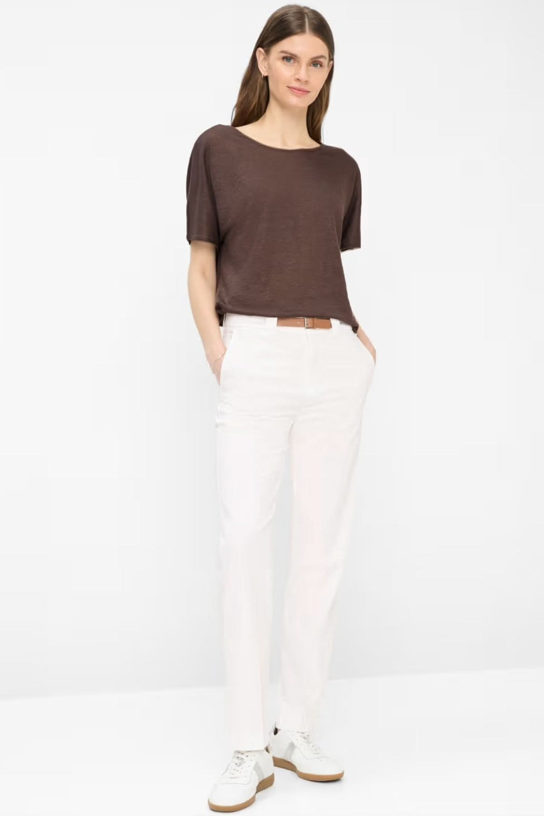 Femme portant un pantalon droit Madison blanc avec ceinture, associé à un haut marron, style élégant et moderne.