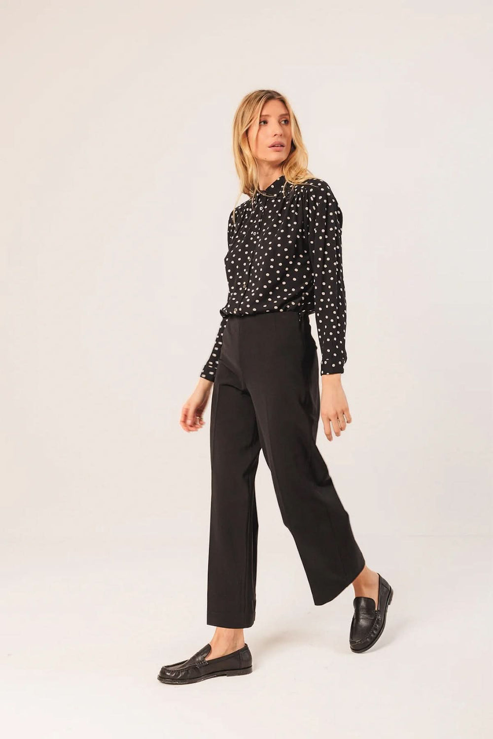 Femme portant un pantalon droit à coupe fluide noir avec une chemise à motifs, soulignant l'élégance et le confort.