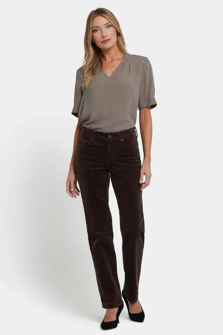 Femme portant un Pantalon droit en velours côtelé extensible marron, style chic avec blouse fluide.