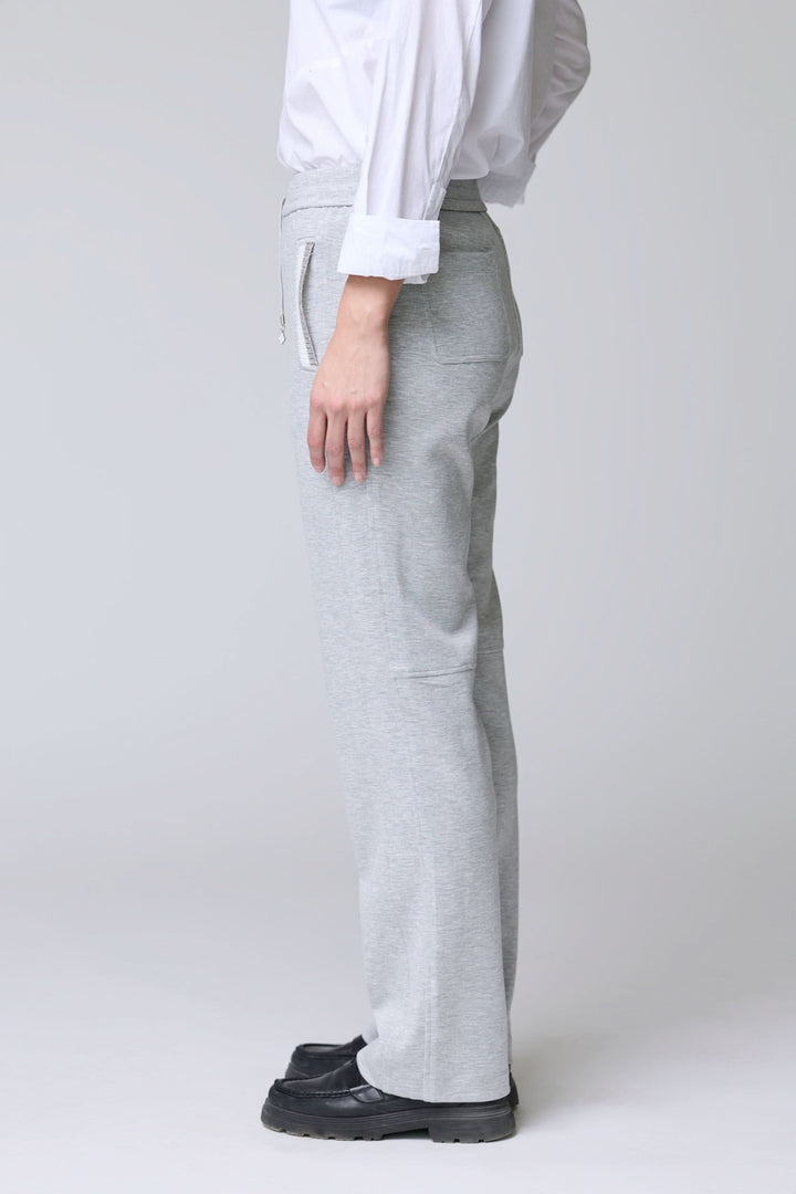 Homme portant un pantalon en jersey ajustable gris avec poches et cordon, offrant confort et style décontracté pour les sorties et détente.