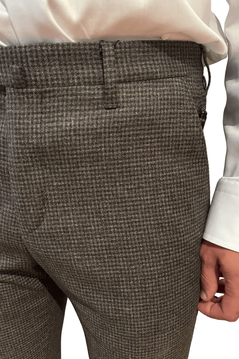 Pantalon en laine à carreaux gris, coupe ajustée, détails élégants avec poches zippées et boutons.