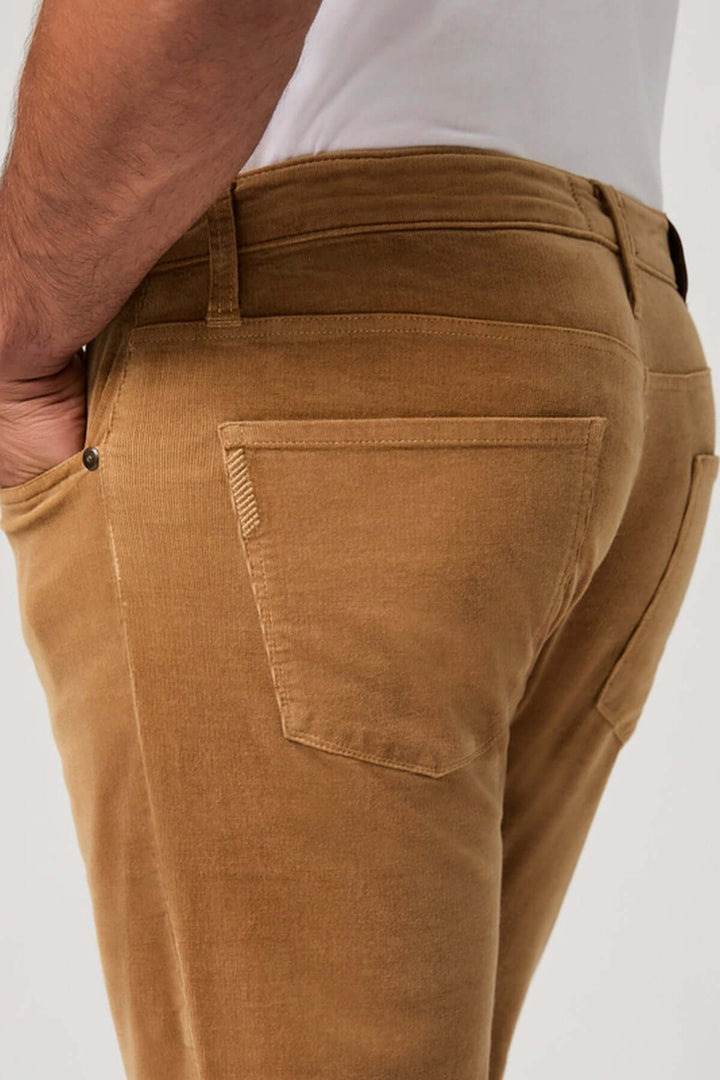 Homme portant un pantalon en micro corduroy velours côtelé marron, offrant confort et élégance décontractée avec une coupe ajustée.