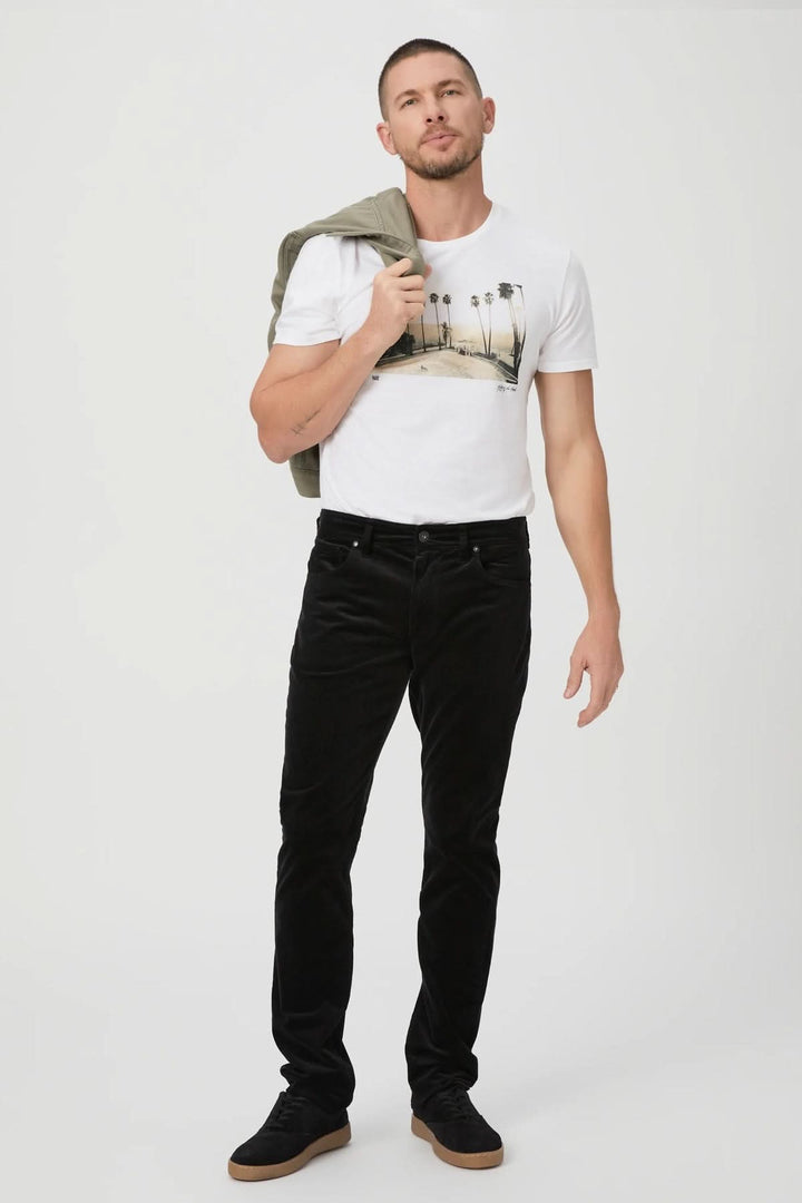 Homme portant un pantalon en micro corduroy noir, style décontracté et élégant, avec un t-shirt blanc et une veste.