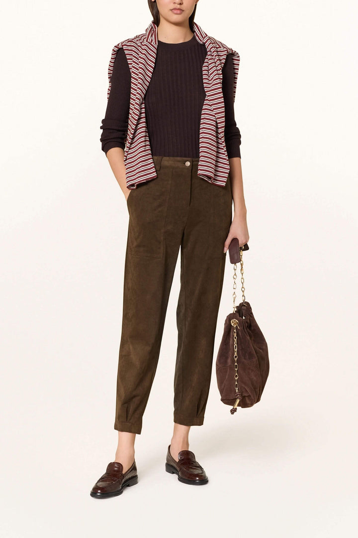 Femme portant un pantalon en suédine à pinces avec une tenue chic et décontractée, illustrant le confort et l'élégance décrits.