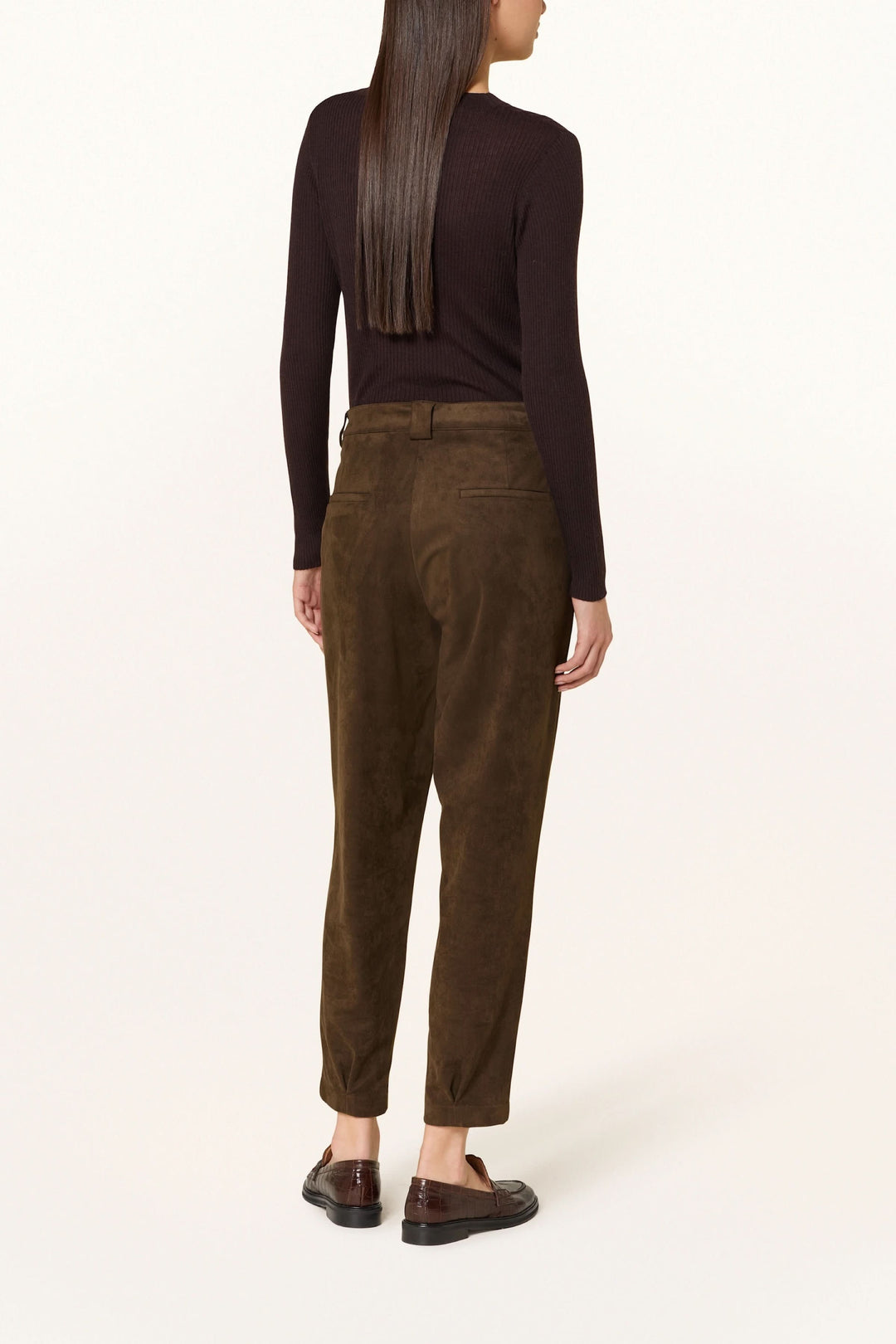 Femme portant un pantalon en suédine à pinces, chic et décontracté, avec taille mi-haute et coupe légèrement fuselée, vu de dos.