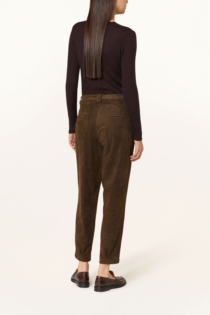 Femme portant un pantalon en suédine à pinces, chic et décontracté, avec taille mi-haute et coupe légèrement fuselée, vu de dos.