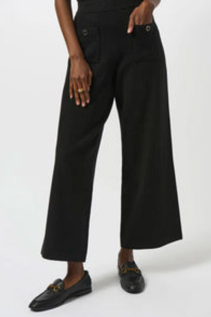 Pantalon en tricot noir ample avec jambe large, taille haute et poches avant décoratives.