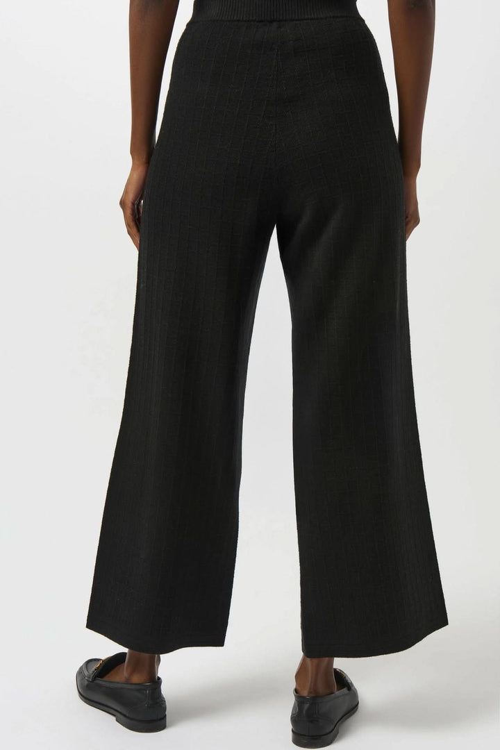 Pantalon noir en tricot, ample et fluide, jambe large avec taille haute et poches avant décoratives.