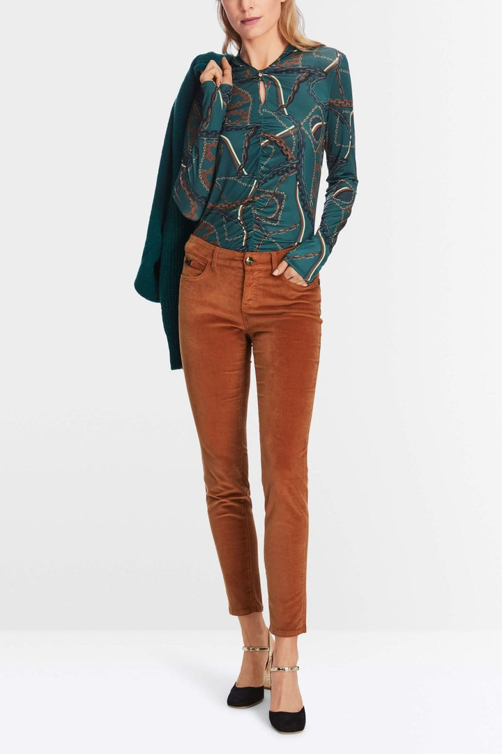 Femme portant un pantalon en velours slim avec une blouse imprimée, style décontracté et chic.