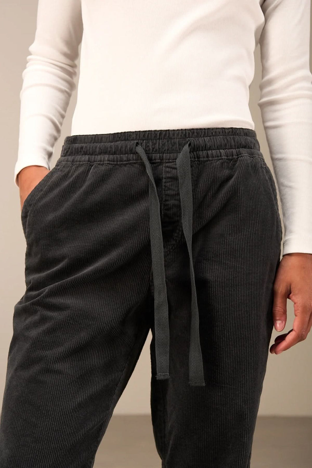 Pantalon en velours côtelé noir avec taille élastique et cordon ajustable, idéal pour un style décontracté et confortable.