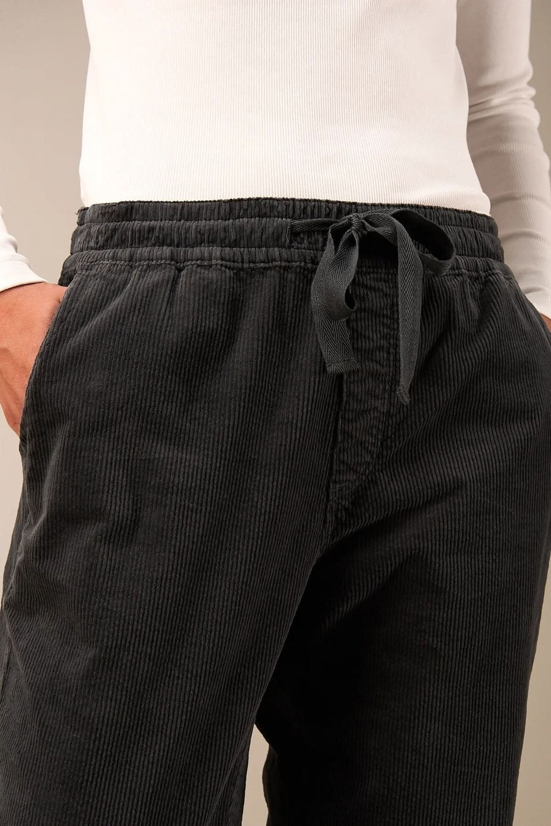 Pantalon en velours côtelé noir avec taille élastique et cordon, offrant confort et style décontracté.