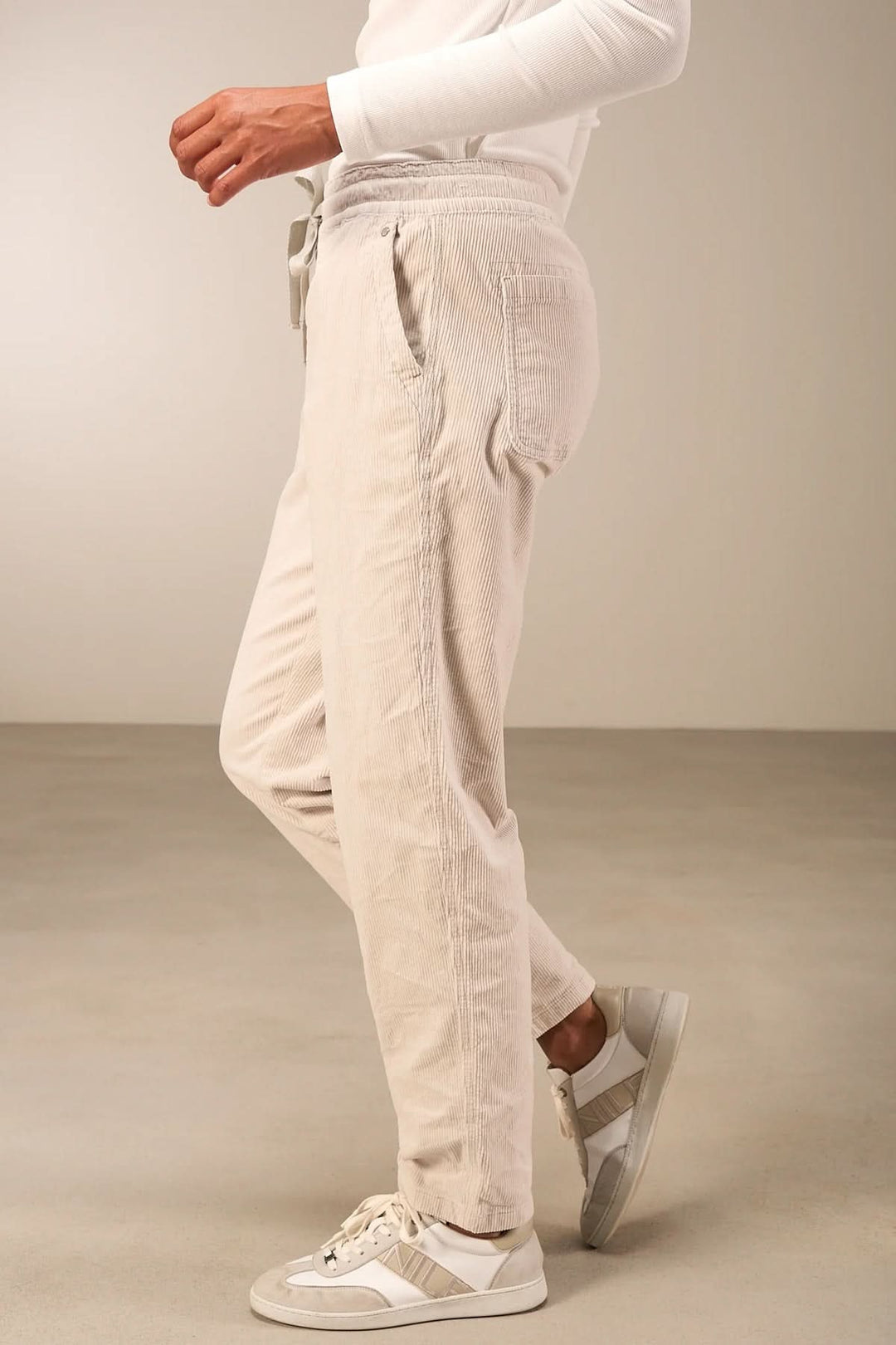 Homme portant un pantalon en velours côtelé beige avec taille élastique et cordon ajustable, style décontracté et confortable.