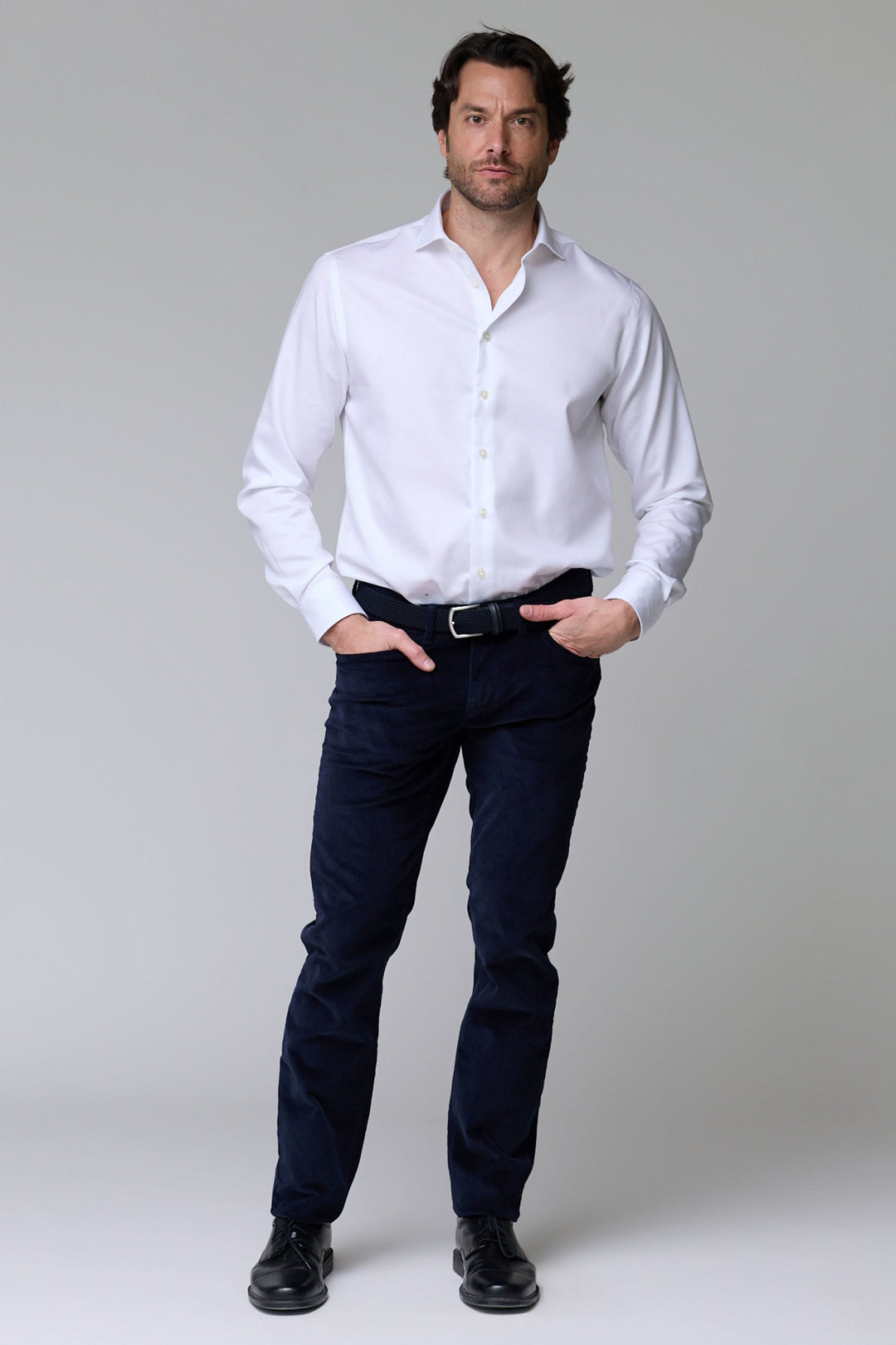 Homme portant un pantalon en velours côtelé noir avec chemise blanche, style décontracté et élégant pour la saison froide.