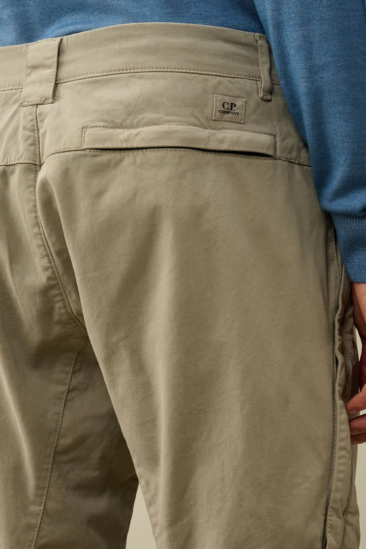 Détail du pantalon en satin extensible avec poches arrière et logo brodé visible.