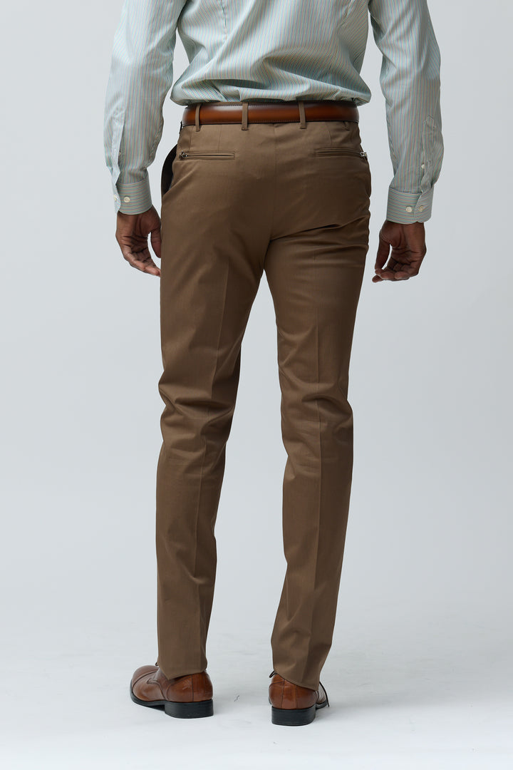 Homme portant un pantalon habillé coupe ajustée marron, vue arrière, avec chemise et chaussures en cuir élégantes.