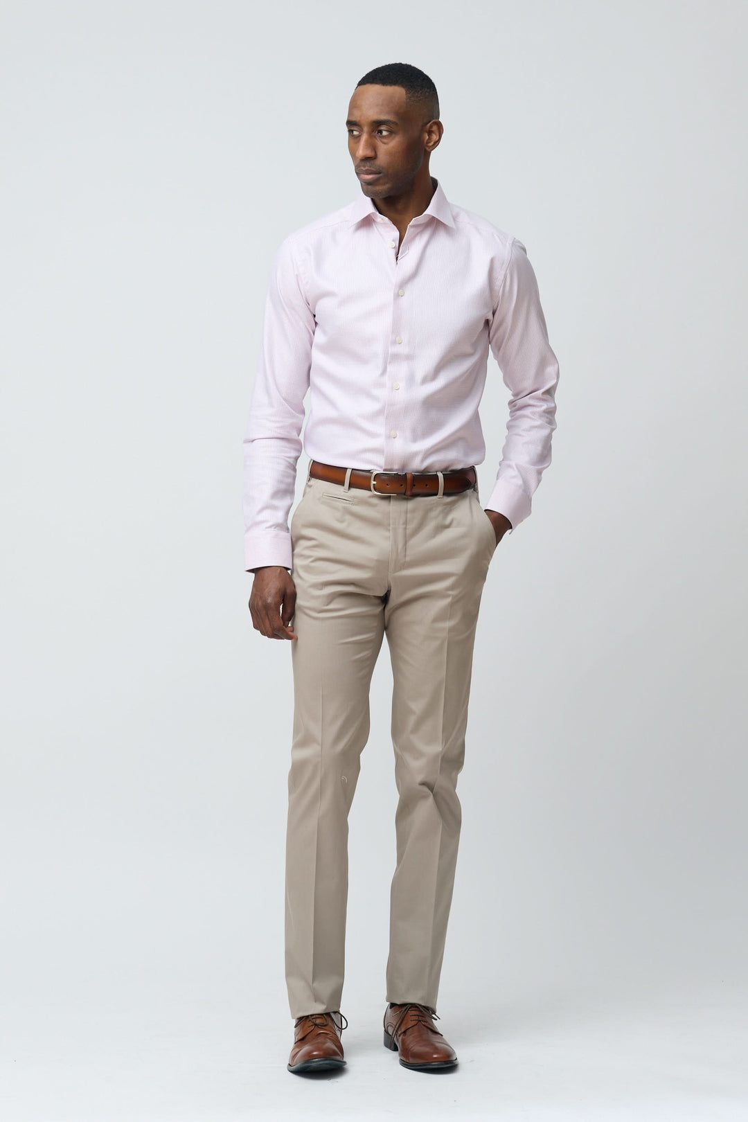 Homme portant un pantalon habillé coupe ajustée et chemise rose, style élégant et professionnel.