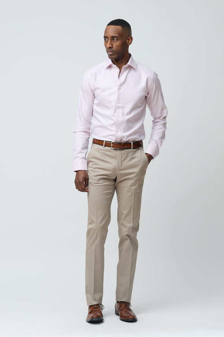 Homme portant un pantalon habillé coupe ajustée et chemise rose, style élégant et professionnel.